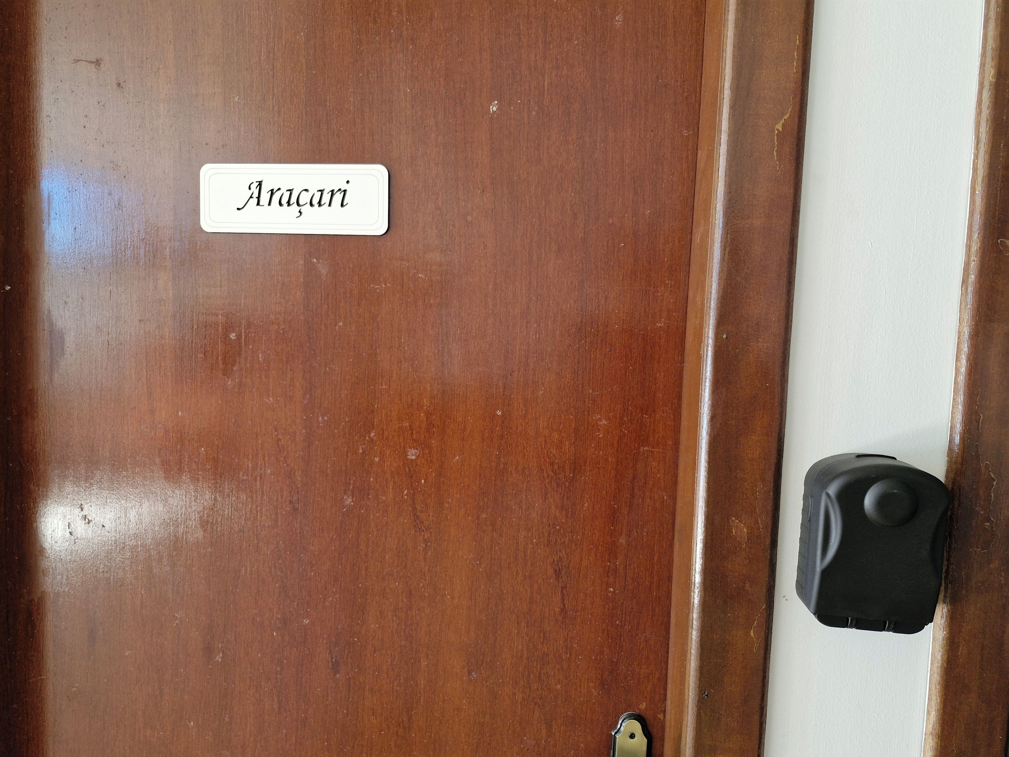 Una puerta de madera con una placa que dice 'Aragani' y un pomo negro.