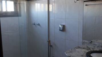 A bathroom with a glass-enclosed shower, a toilet, and a sink with a marble countertop.