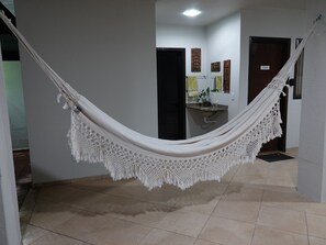 A hammock in a hallway with a tiled floor, a sink, and a door labeled 'Alegan'. - Pousada Solar dos Passaros (Rondonópolis)