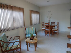 A room with a dining table, chairs, a sofa, and a small round table with a plant. - Pousada Solar dos Passaros (Rondonópolis)