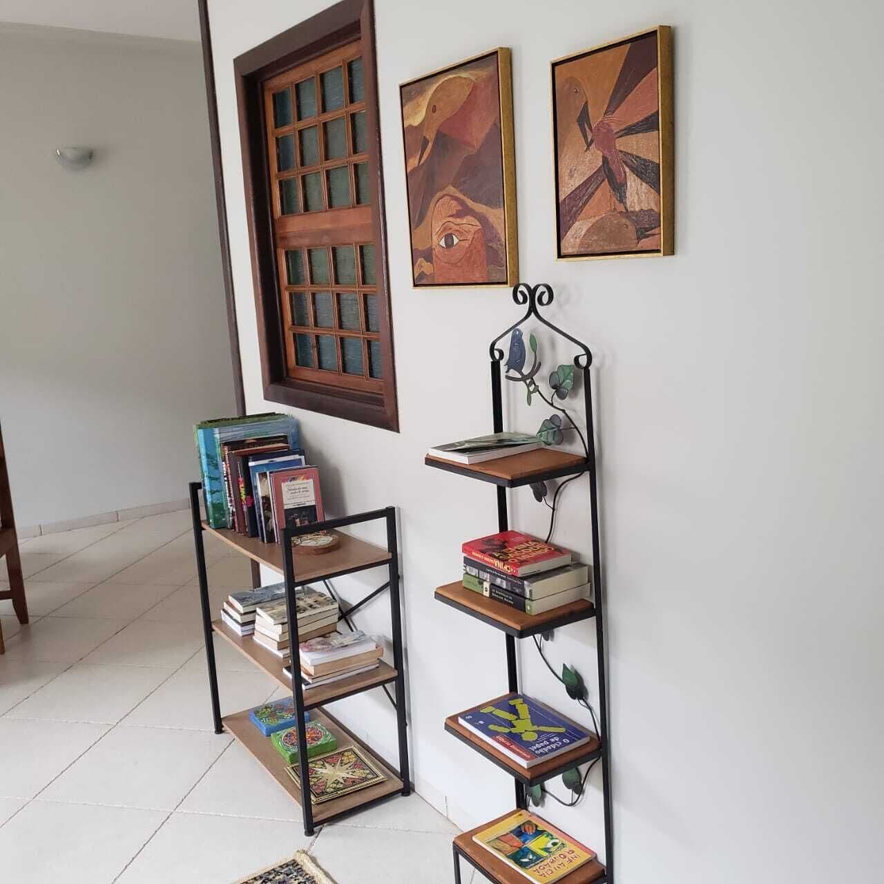 A room with a bookshelf, a window, and two paintings on the wall.