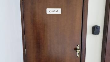 Una puerta de madera cerrada con una placa identificadora que dice 'Cardinal' y un picaporte.