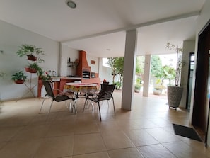 Een ruime eethoek met een ronde tafel, stoelen en potplanten.