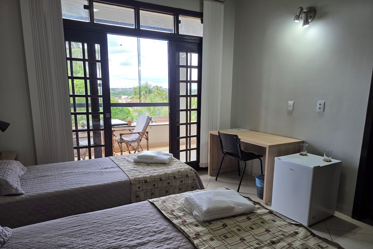 Een hotelkamer met twee bedden, een bureau, een stoel en een koelkast.