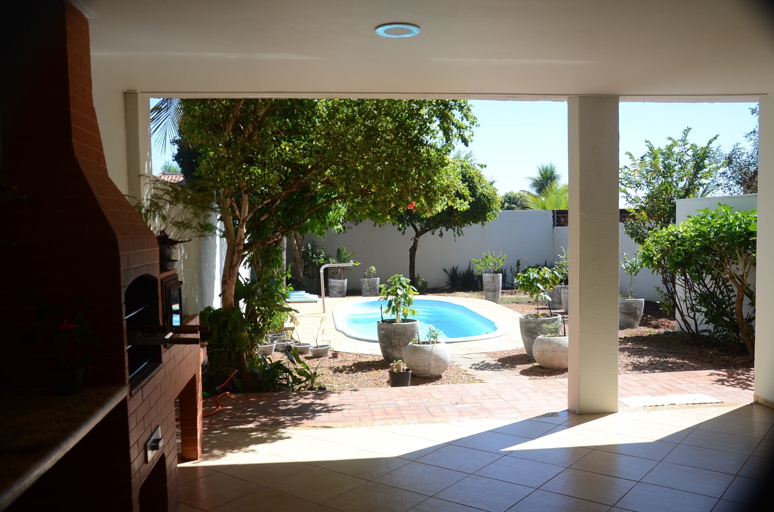 Um pátio com piscina, cercado por plantas em vasos e um muro de tijolos.