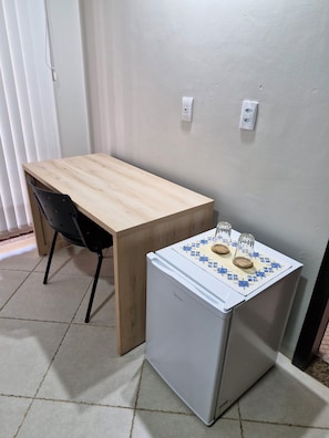 A small kitchenette with a wooden table and a refrigerator.