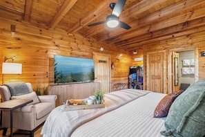A cozy cabin-style room with a bed, a television, a desk, and a fireplace. - Hot Tub & Play Tent | Near Dollywood (Sevierville)