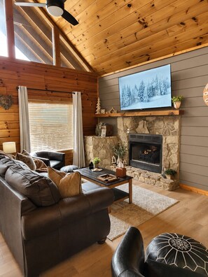 A cozy living room with a fireplace, a television mounted above it, and a comfortable seating area. - Hot Tub & Play Tent | Near Dollywood (Sevierville)