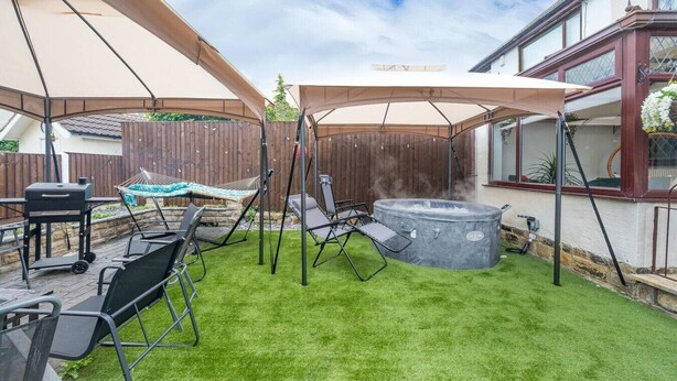 Ein Garten mit Whirlpool, Hängematte und Grillplatz.