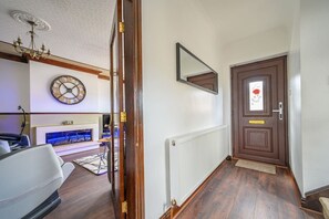 Ein Flur mit Holzboden, einem weißen Heizkörper, einer braunen Tür mit roter Blütensticker und einem an der Wand befestigten Spiegel.