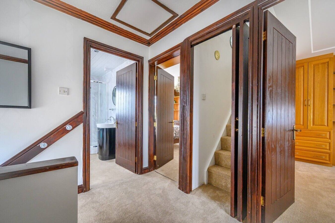 A hallway with wooden doors, a staircase, and a bathroom visible in the background.