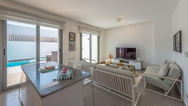 A modern living room with a flat-screen TV, a dining area with a glass table, and a balcony with a pool view. - Luxury Villa with private pool Sholan 2 (Red Sea Governorate)