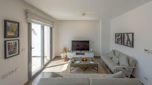 A modern living room with a sofa, a coffee table with fruit, a flat-screen TV, and a sliding glass door leading to a balcony. - Luxury Villa with private pool Sholan 2 (Red Sea Governorate)