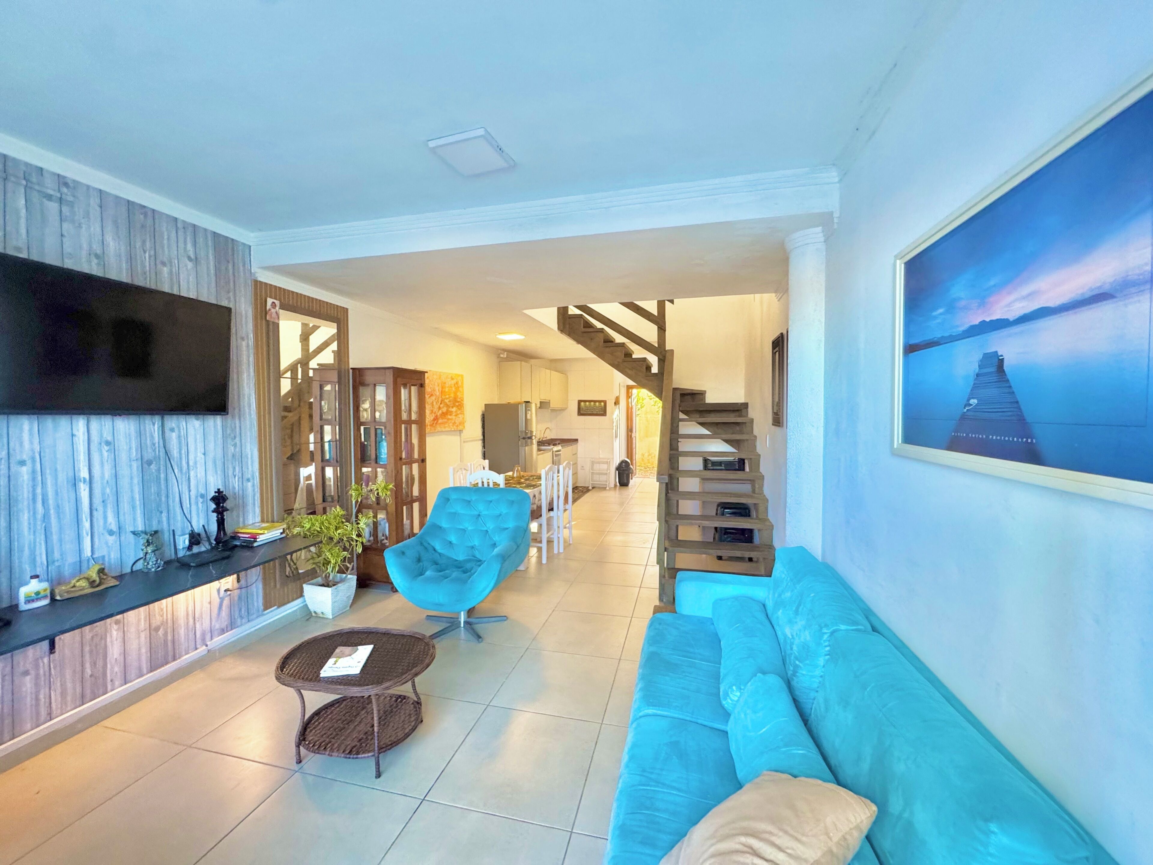 A modern living room with a sofa, armchair, and a television mounted on the wall.