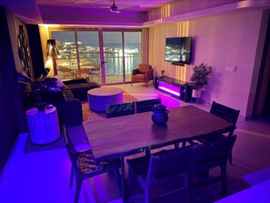 Een moderne woonkamer met een eethoek, grote ramen en uitzicht op een stadsgezicht.
