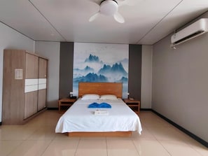 Quarto de hotel com cama, ventoinha no teto, ar condicionado fixado na parede e guarda-roupa de madeira.