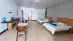 A hotel room with two beds, a small round table, a wooden chair, a desk with a kettle, and a water dispenser. - MERMAID N2 (Honiara)