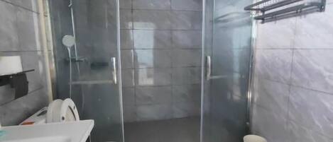 A modern bathroom with a glass shower enclosure, a white sink, and a toilet.