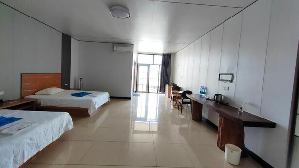 A hotel room with two beds, a desk, a chair, a small table, a window, and a bathroom. - MERMAID N2 (Honiara)