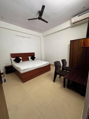 Un dormitorio con cama, escritorio, silla, armario y ventilador de techo.
