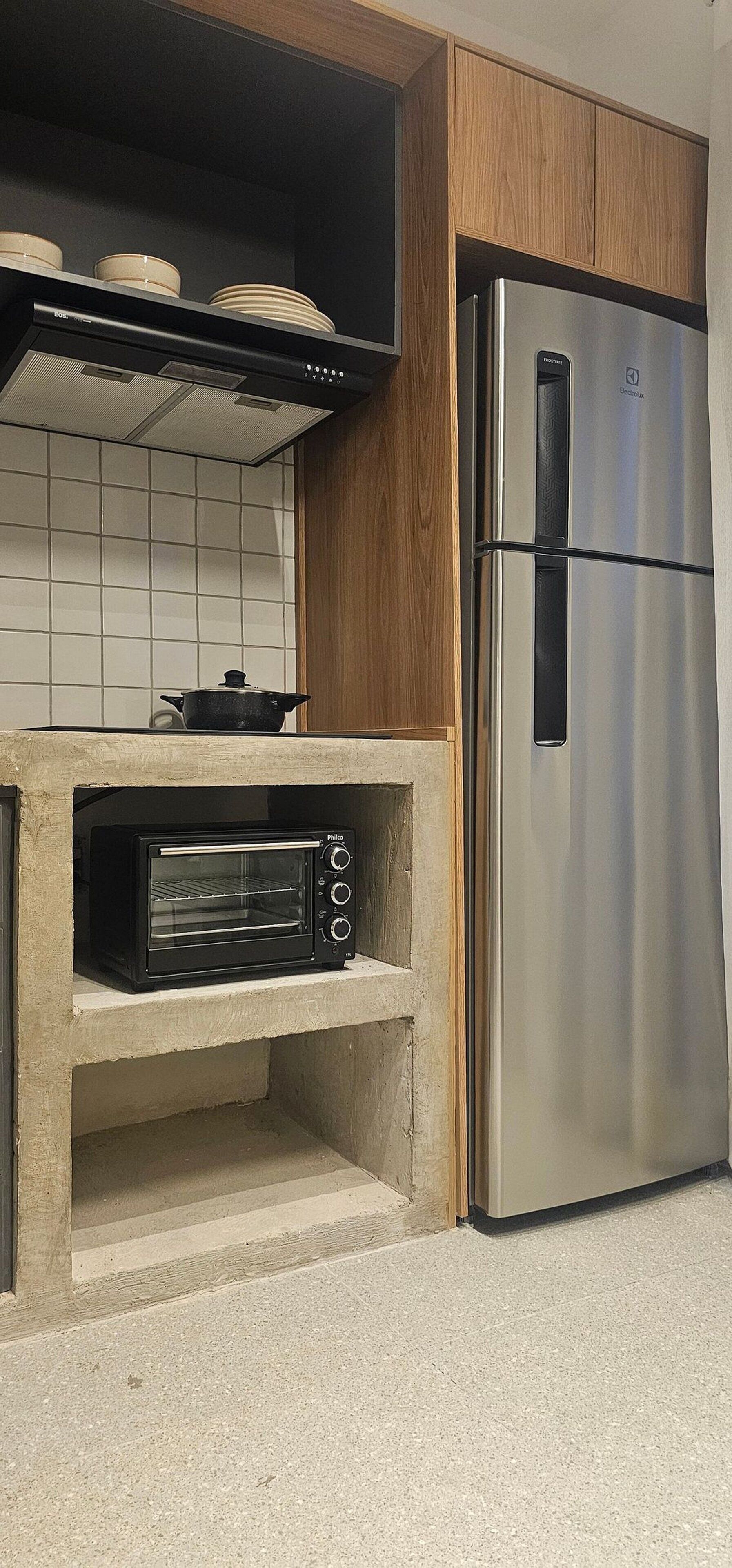 A kitchen with a built-in oven, a stainless steel refrigerator, and a tiled backsplash.