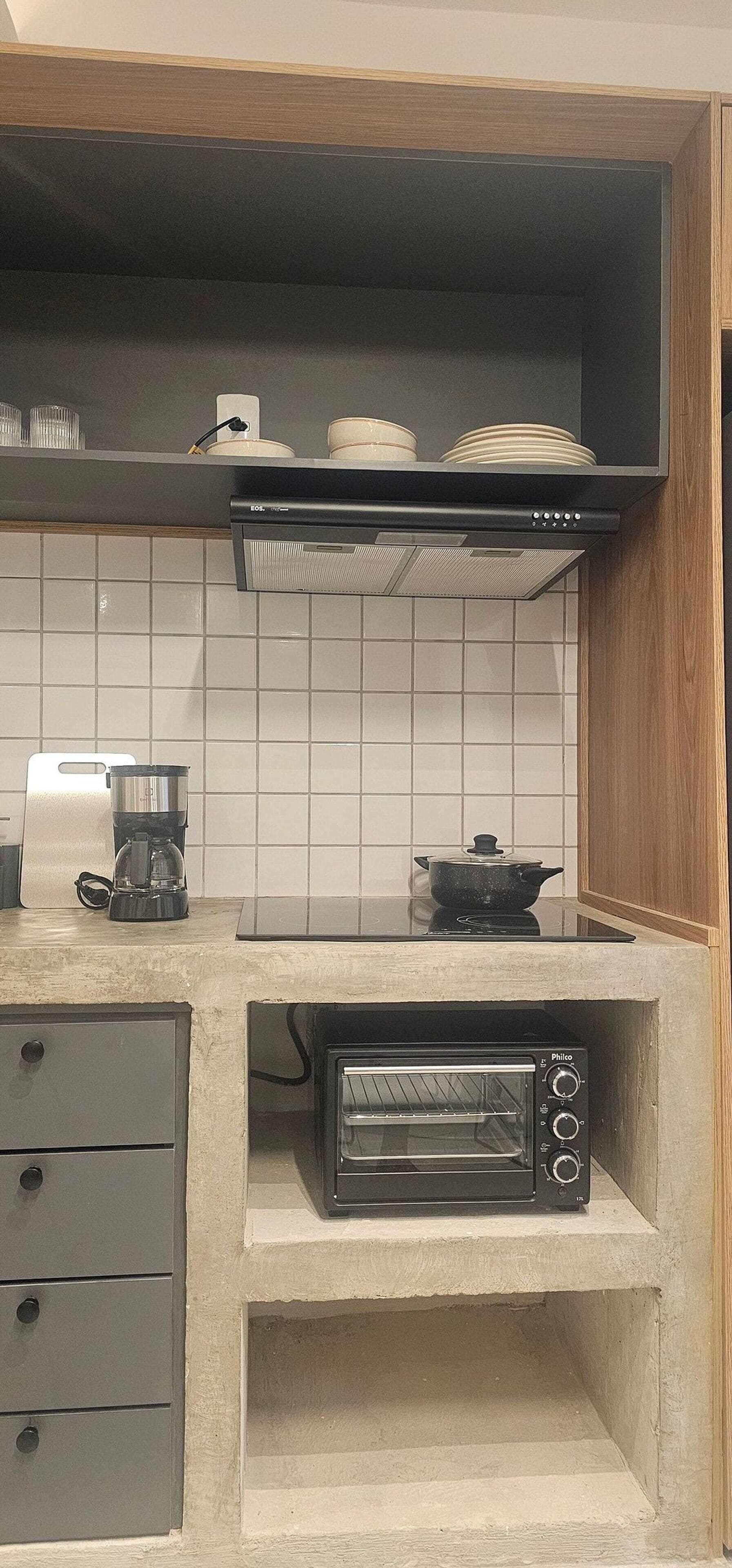 A kitchen with a built-in toaster oven, a coffee maker, and a pot on the counter.