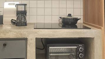 A kitchen with a built-in toaster oven, a coffee maker, and a pot on the counter.