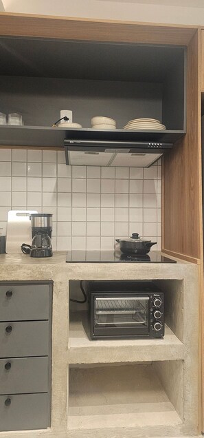 A kitchen with a built-in toaster oven, a coffee maker, and a pot on the counter. - Cond. Metro Casa Centro 101 (São Paulo)