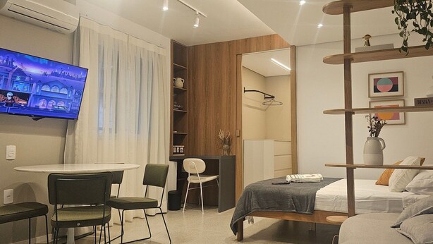 Habitació d'hotel moderna amb un llit, un escriptori, una cadira, una televisió i una biblioteca.