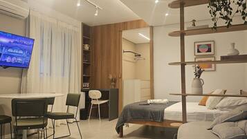 Una habitación de hotel moderna con cama, escritorio, silla, televisión y estantería.