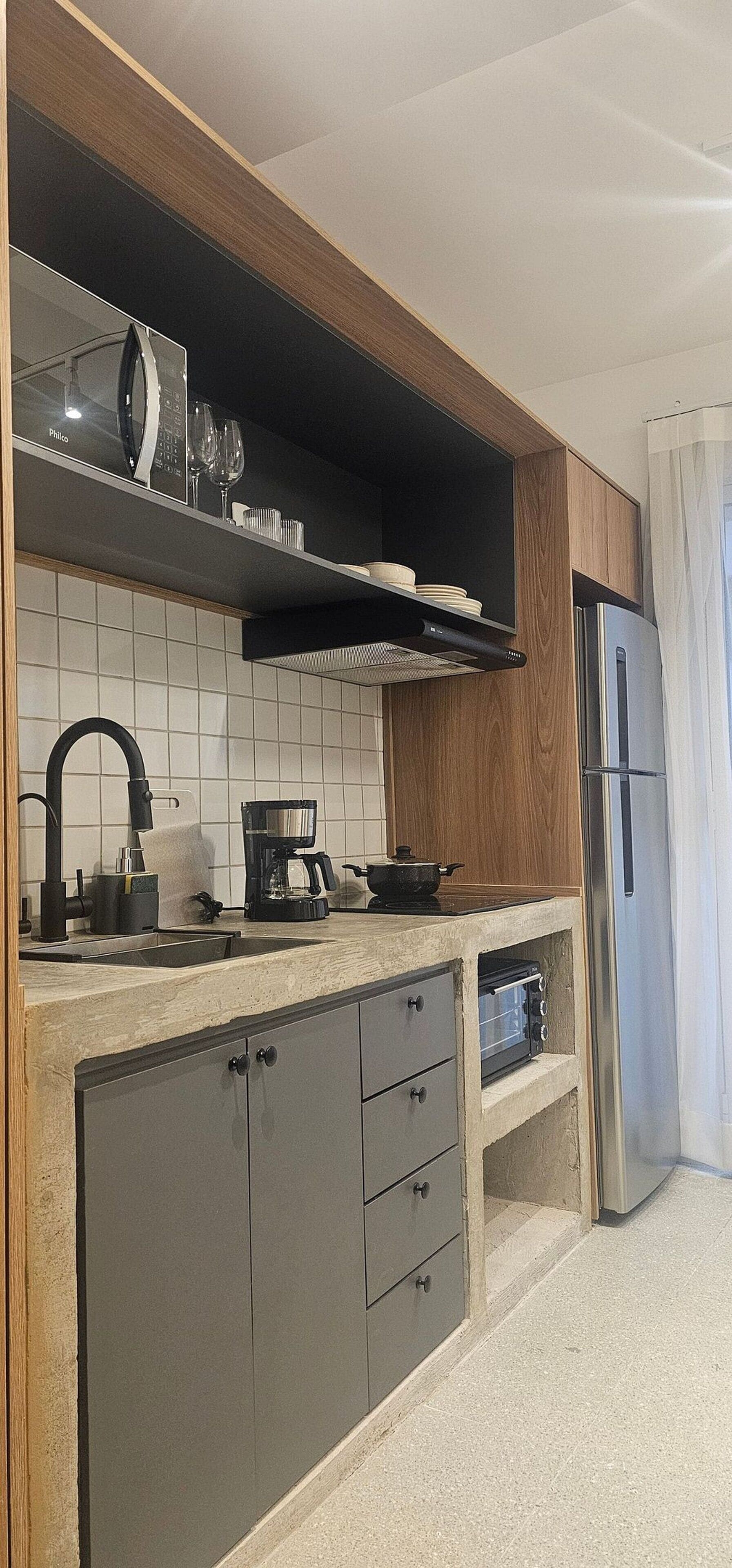 A modern kitchen with a built-in microwave, a coffee maker, and a stainless steel refrigerator.