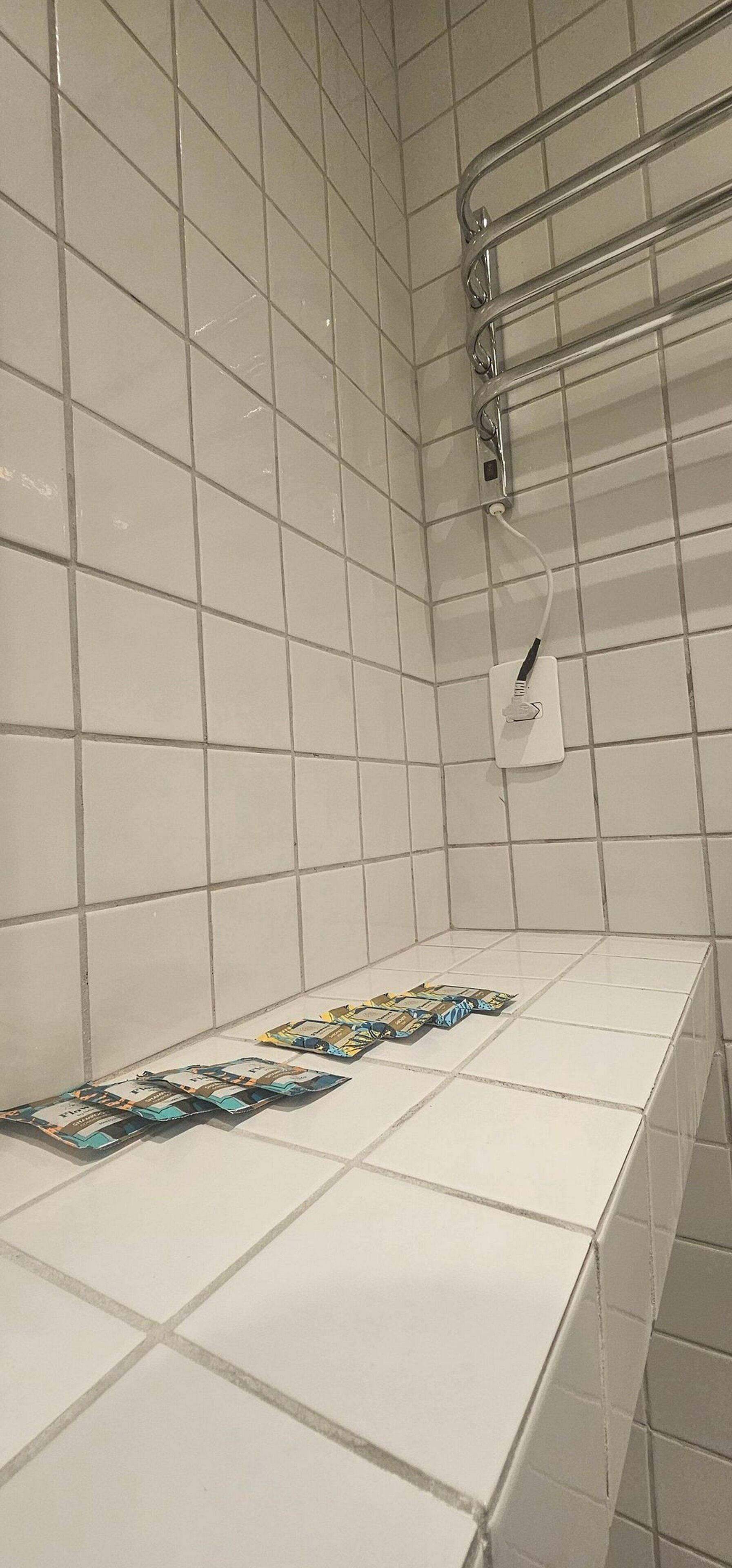 Een badkamer met witte betegelde wanden, een douchegedeelte en een handdoekrek.