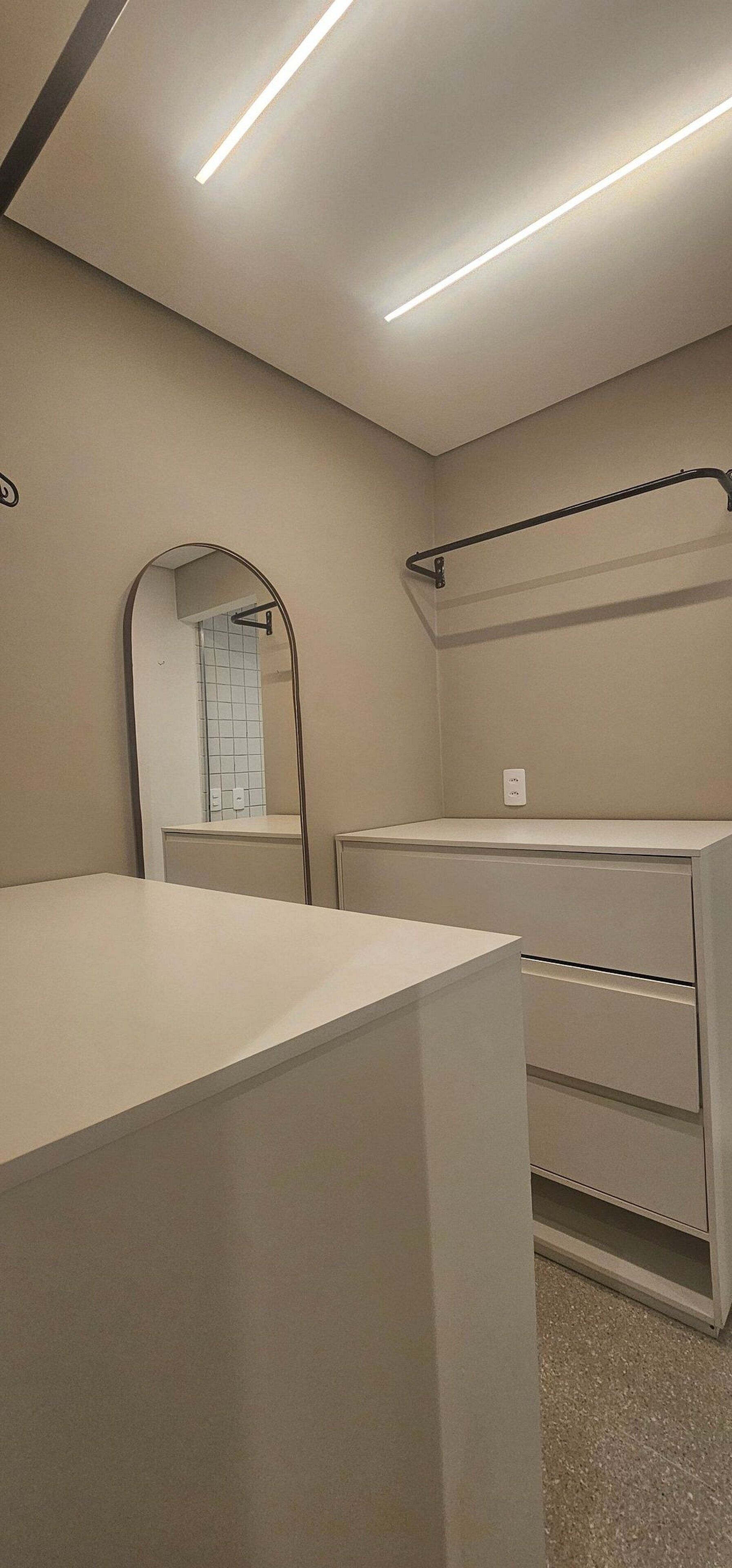 A modern bathroom with a mirror, a towel rack, and a countertop.