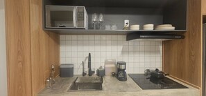 Une cuisine compacte équipée d’un four à micro-ondes, d’une machine à café et d’un petit évier.