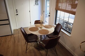 A dining area with a round table, four chairs, and a window with a view. - Stay Smooth ATX/ Stylish,Quiet Home Base Near the Domain. (Austin)
