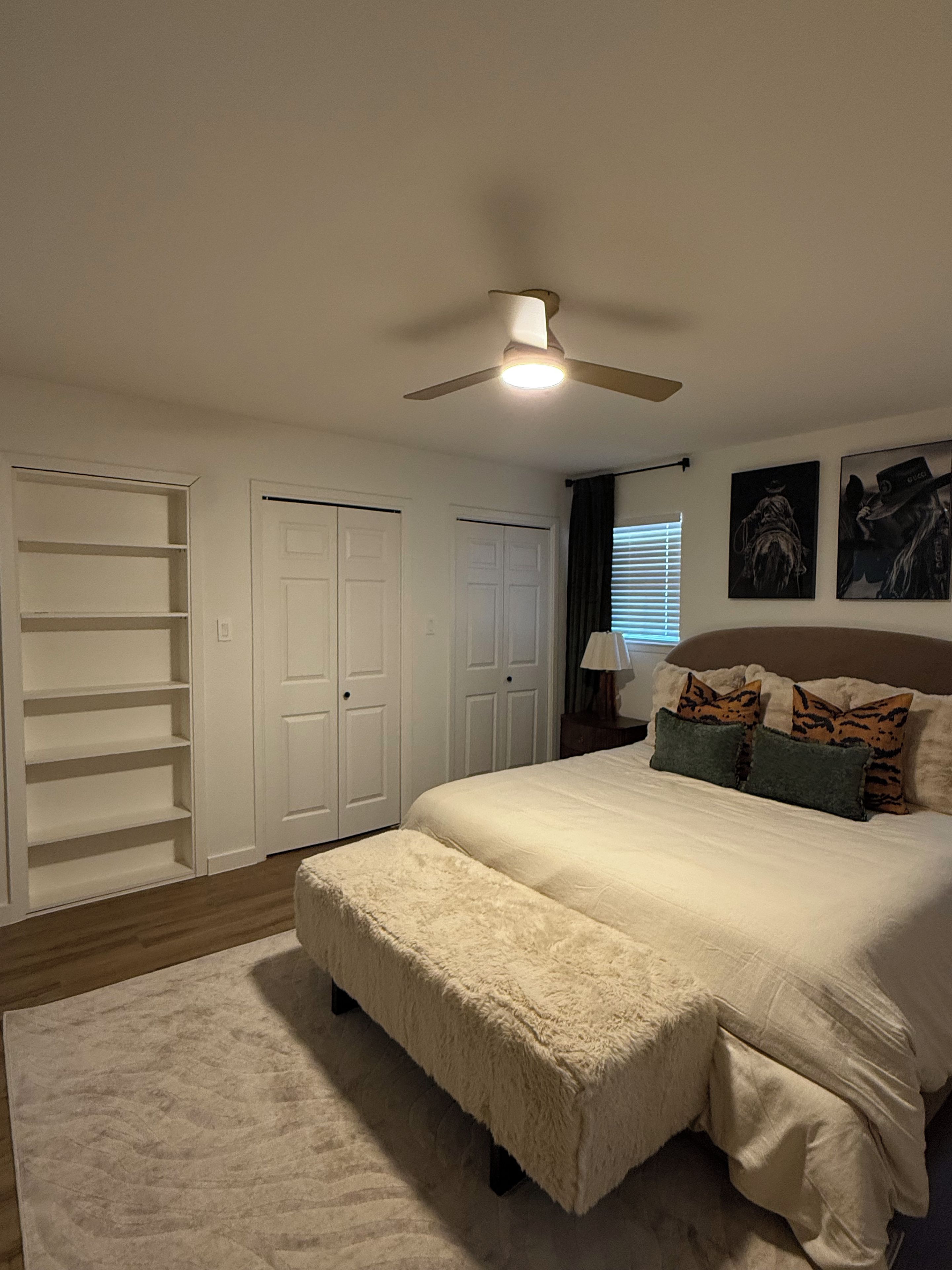 A bedroom with a large bed, a ceiling fan, and a wardrobe.