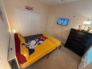 Ein Schlafzimmer mit einem Bett, einem Schminktisch, einem Fernseher und einer Tür.