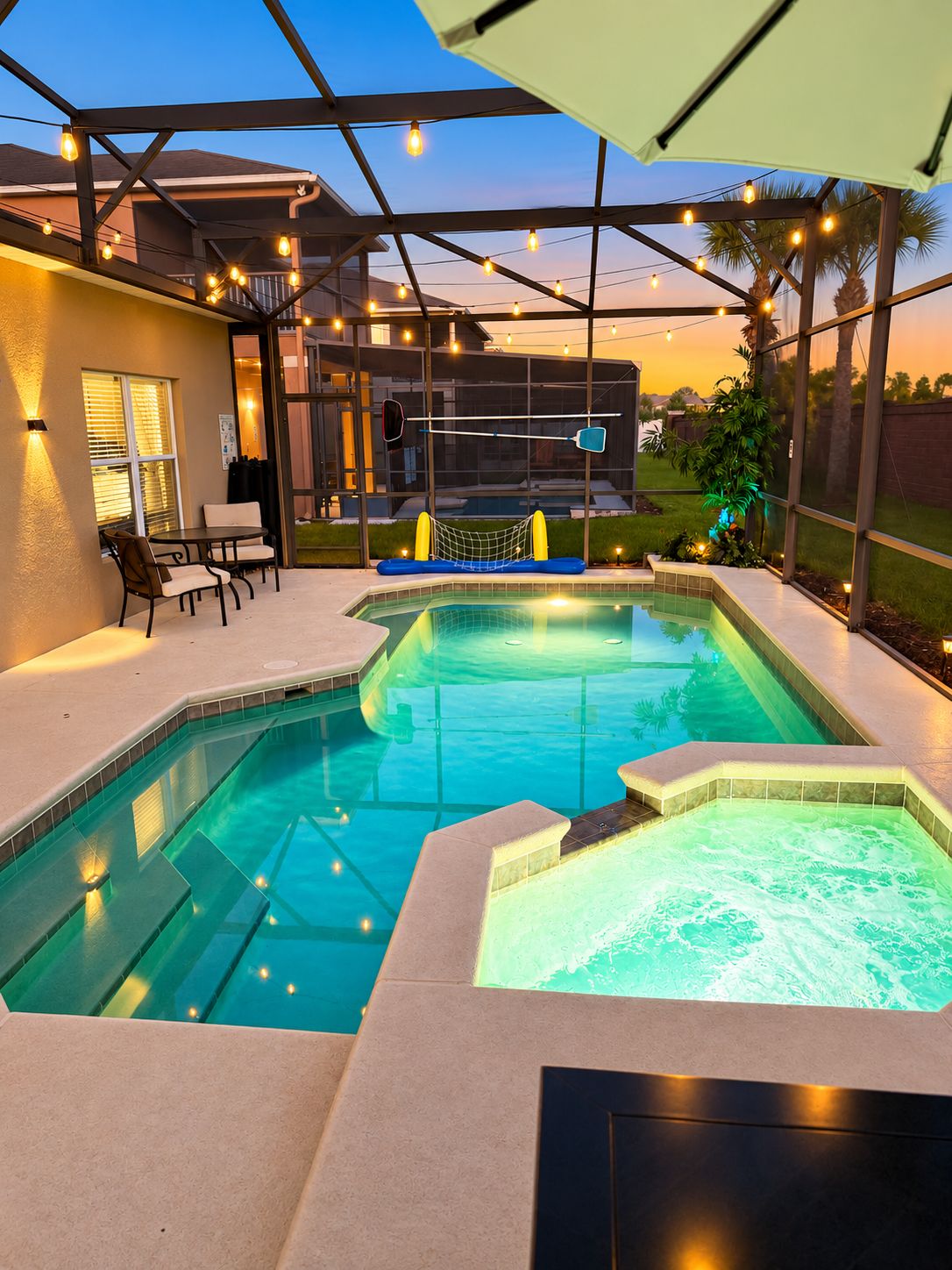 Ein Swimmingpool mit Whirlpool, umgeben von einer überdachten Terrasse mit Sitzgelegenheiten und Lichterketten.