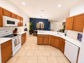 A modern kitchen with wooden cabinets, a central island, a microwave, stove, and dishwasher. - Family Villa, Private pool, cinema, and game room. (Davenport)