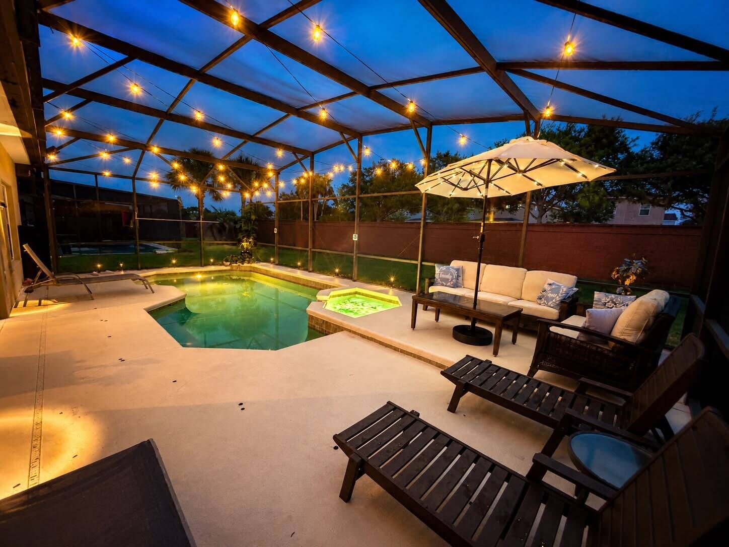 Un patio exterior con piscina, sillas de descanso y un área de estar cubierta.