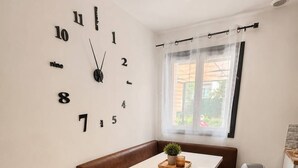 A modern kitchen with a white table, brown bench, and a wall clock. - House near Paris • Private Jacuzzi • 7 passengers (Sarcelles)