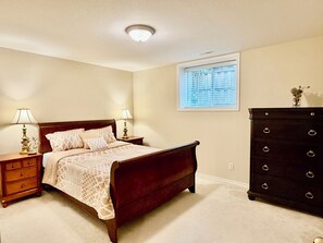 Un dormitorio con cama, mesitas de noche, cómoda y ventana con persianas.