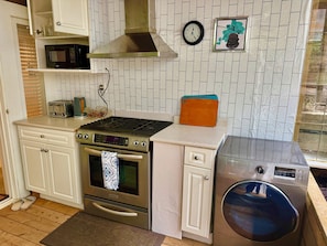 A compact kitchen with a microwave, toaster, stove, oven, and washing machine. - hot tub villa with a sauna room (Surrey)