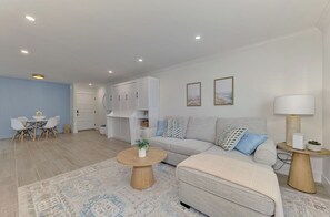 Ein modernes Wohnzimmer mit einer Couch, einem Couchtisch und einem Essbereich mit Stühlen.