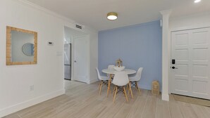 Moderni ruokailutila, jossa on pyöreä pöytä ja tuolit, valkoinen ovi ja sininen seinä.