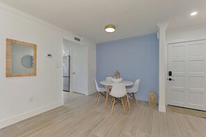 Ein moderner Essbereich mit einem runden Tisch und Stühlen, einer weißen Tür und einer blauen Wand.