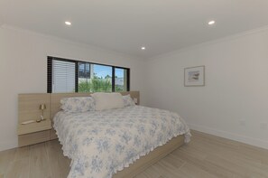 A bedroom with a bed, bedside table, lamp, window with blinds, and a framed picture on the wall. - Newly renovated 1-bed/bath condo sleeps 6! Walking distance to the beach! (Siesta Key)