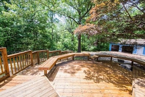 A wooden deck with a curved railing, surrounded by dense green foliage. - Experience Stunning Scenic Views! (Knoxville)
