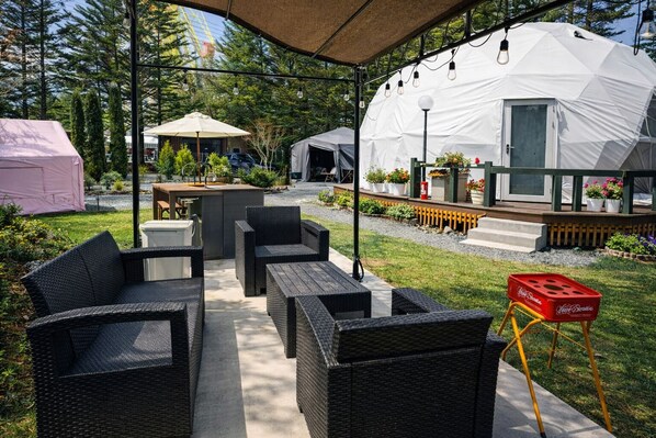 An outdoor patio area with wicker furniture, a table, and a barbecue grill.