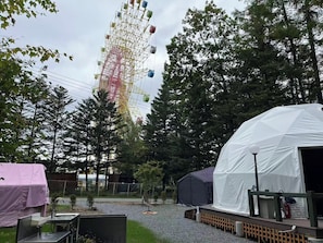 A Ferris wheel, tents, and a covered area, likely a campsite or temporary accommodation.